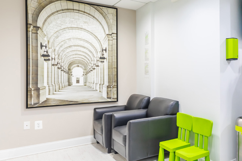 a living room with a couch, chair, and a painting  at RTC Dental in Sterling for Cosmetic dentist Reston services.