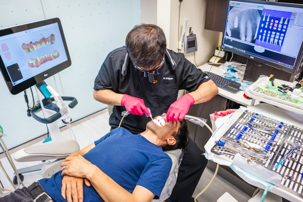 a man is cutting a man's hair with a pair of scissors  at RTC Dental in Arlington for Teeth whitening Reston services.