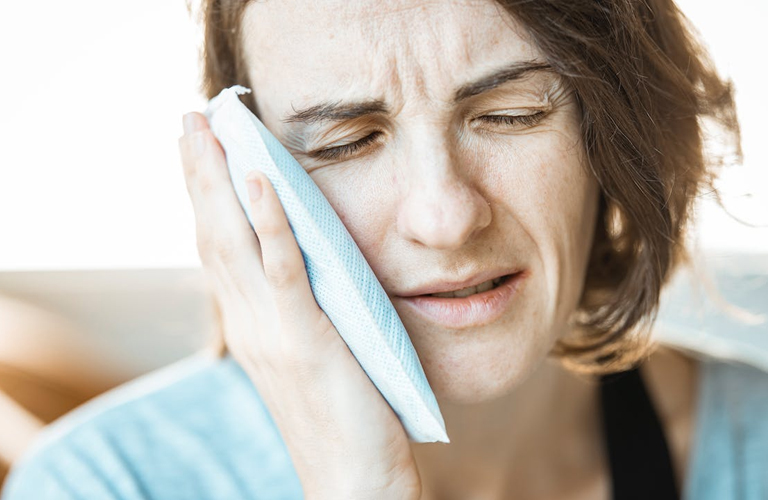 woman holding mouth in pain at RTC Dental in Great Falls for Reston dental office services.