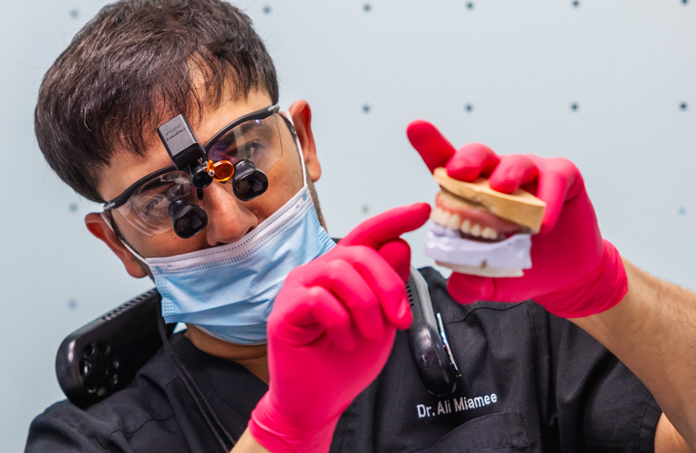 a man with a mask on holding dental tools at RTC Dental in Ashburn for RTC Dental Reston services.