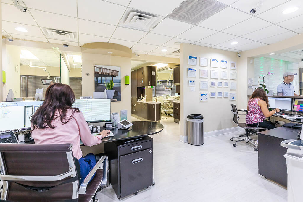 a woman is working at a desk in a large office  at RTC Dental in Vienna for Family dentistry Reston services.