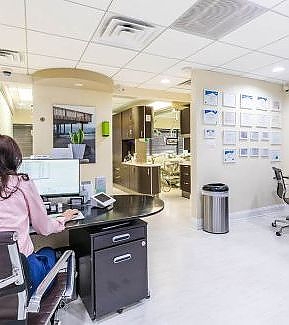 a woman is working at a desk in a large office  at RTC Dental in Vienna for Family dentistry Reston services.