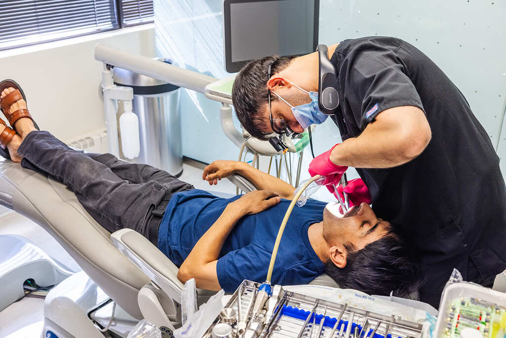 a man laying on a hospital bed with a man in a hospital bed  at RTC Dental in McLean for Invisalign Reston services.