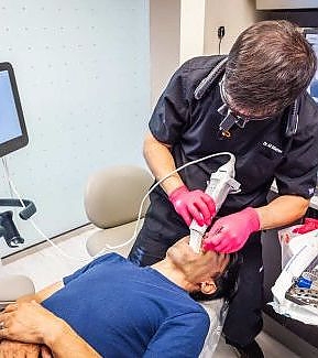 a man is putting a mask on a man's face  at RTC Dental in Arlington for Teeth whitening Reston services.