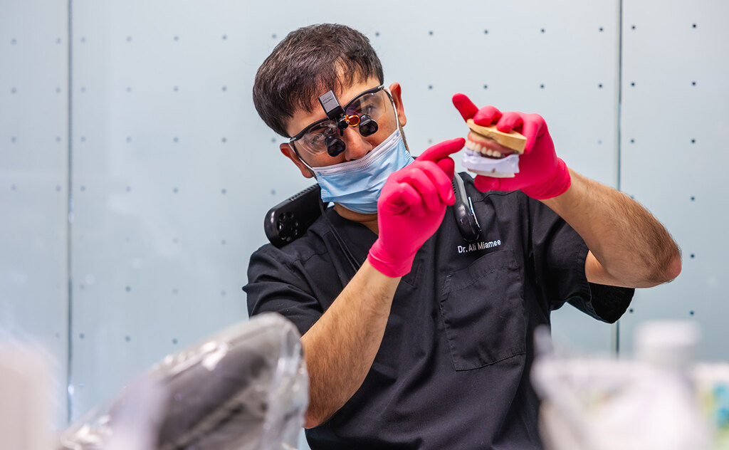 a man with a mask on holding a pair of scissors  at RTC Dental in Reston, VA for Dentist Reston VA services.