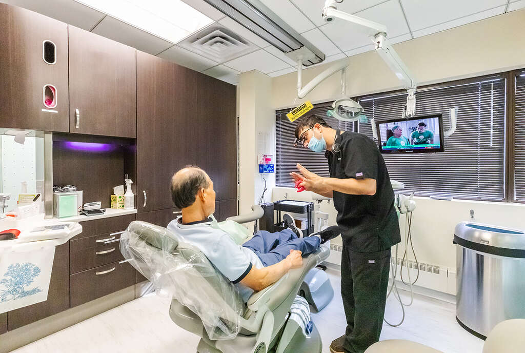 two men in a hospital room with a man in a wheelchair  at RTC Dental in Reston, VA for Emergency dentist Reston services.