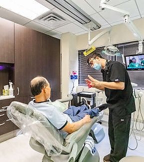 two men in a hospital room with a man in a wheelchair  at RTC Dental in Reston, VA for Emergency dentist Reston services.