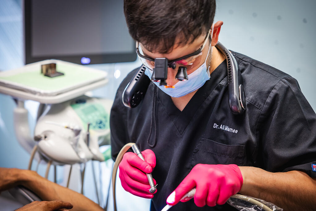 a man in a mask is using a pair of scissors  at RTC Dental in Ashburn for RTC Dental Reston services.