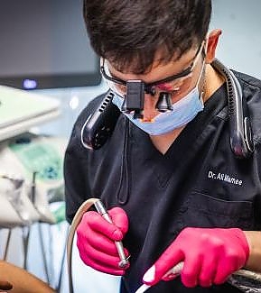 a man in a mask is using a pair of scissors  at RTC Dental in Ashburn for RTC Dental Reston services.