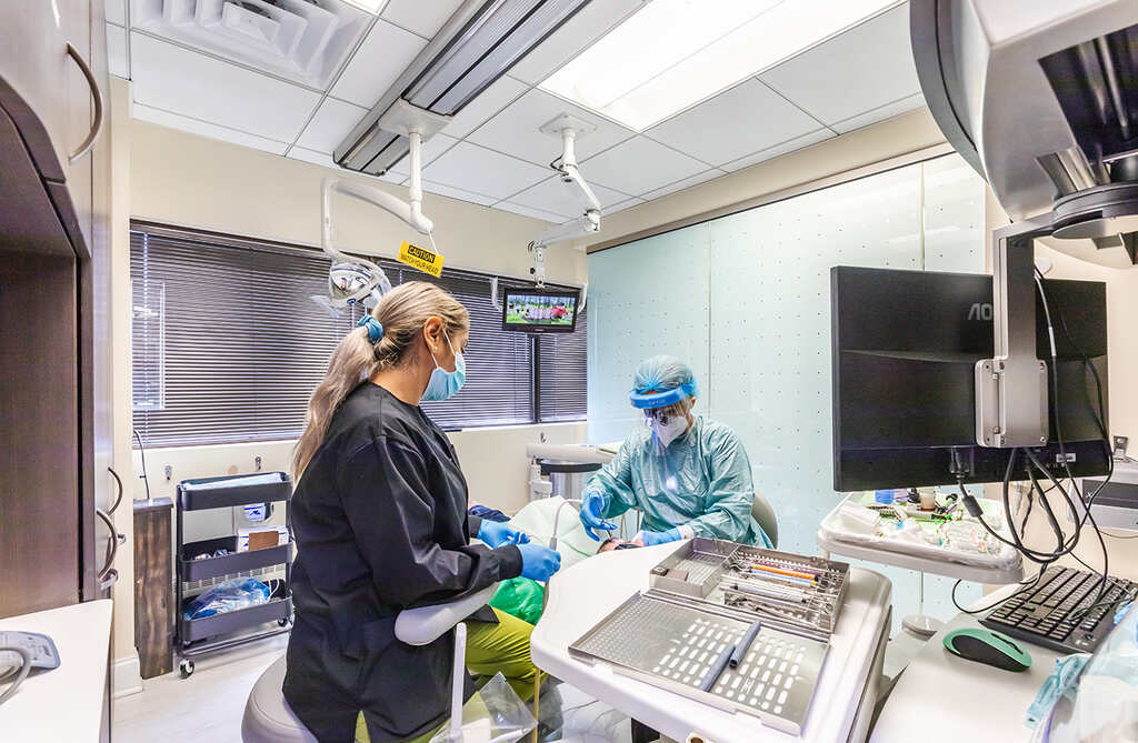 a woman in a hospital gown is working on a machine  at RTC Dental in Arlington for Teeth whitening Reston services.