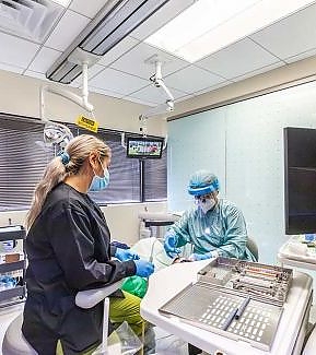 a woman in a hospital gown is working on a machine  at RTC Dental in Arlington for Teeth whitening Reston services.