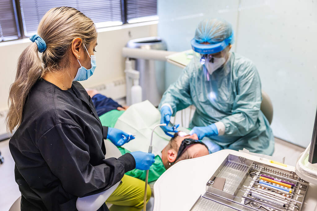 a woman in a hospital gown is cutting a patient's hair  at RTC Dental in Reston, VA for Dentist Reston VA services.