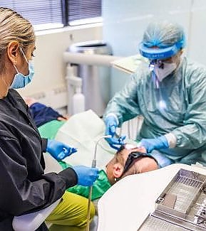 a woman in a hospital gown is cutting a patient's hair  at RTC Dental in Reston, VA for Dentist Reston VA services.